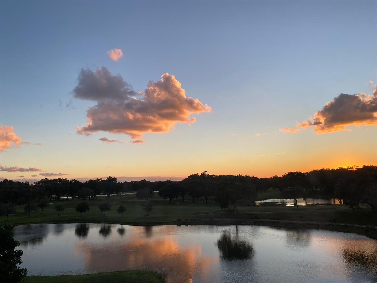 A sunset view over a pond and golf course with scattered trees and clouds — 3001 W Rolling Hills Circle # 501, Davie FL 33328, DAVIE, FL