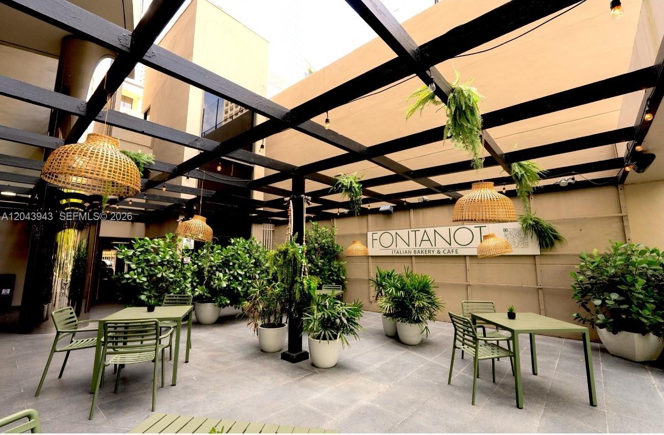 An outdoor patio features green metal furniture, potted plants, and a black wooden pergola — 848 NE Brickell Avenue, Miami FL 33131, MIAMI, FL