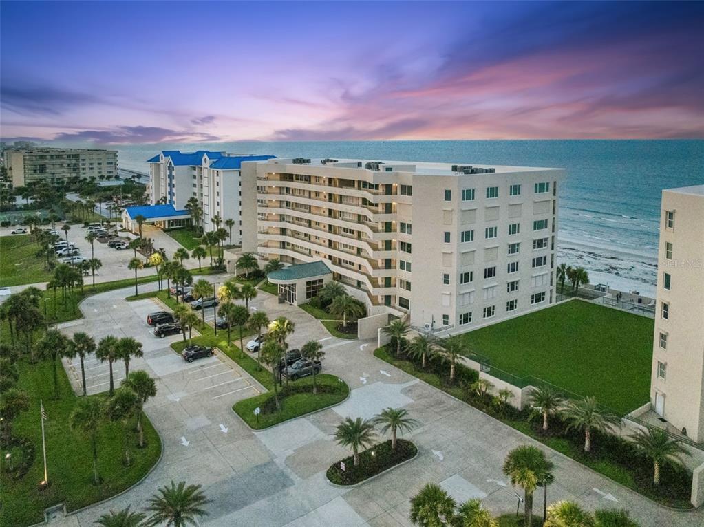 An aerial view of a multi-story beachfront condominium complex with a parking lot and landscaping — 4621 S ATLANTIC AVENUE UNIT 7702, PONCE INLET, FL