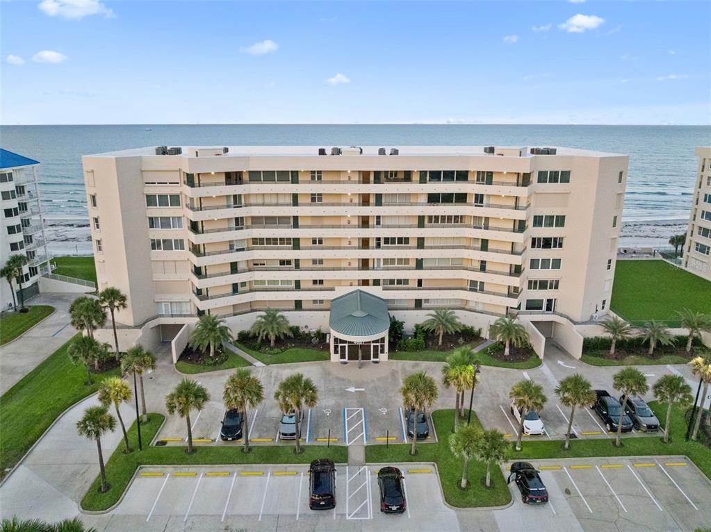 An aerial view of a multi-story beachfront condominium building with a parking lot — 4621 S ATLANTIC AVENUE UNIT 7702, PONCE INLET, FL