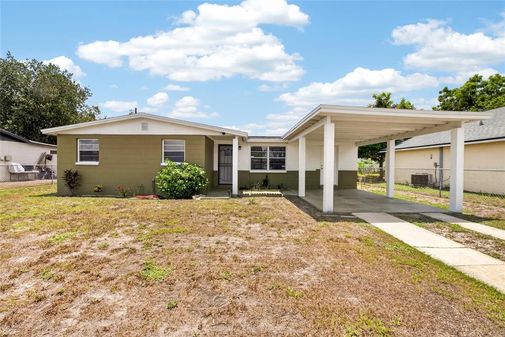 A single-story house with an olive green exterior, a front carport, and a grassy yard — 4706 S 87TH STREET, TAMPA, FL