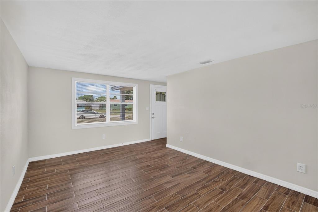 An empty room with light-colored walls, wood-look tile flooring, a window, and a white door — 4706 S 87TH STREET, TAMPA, FL