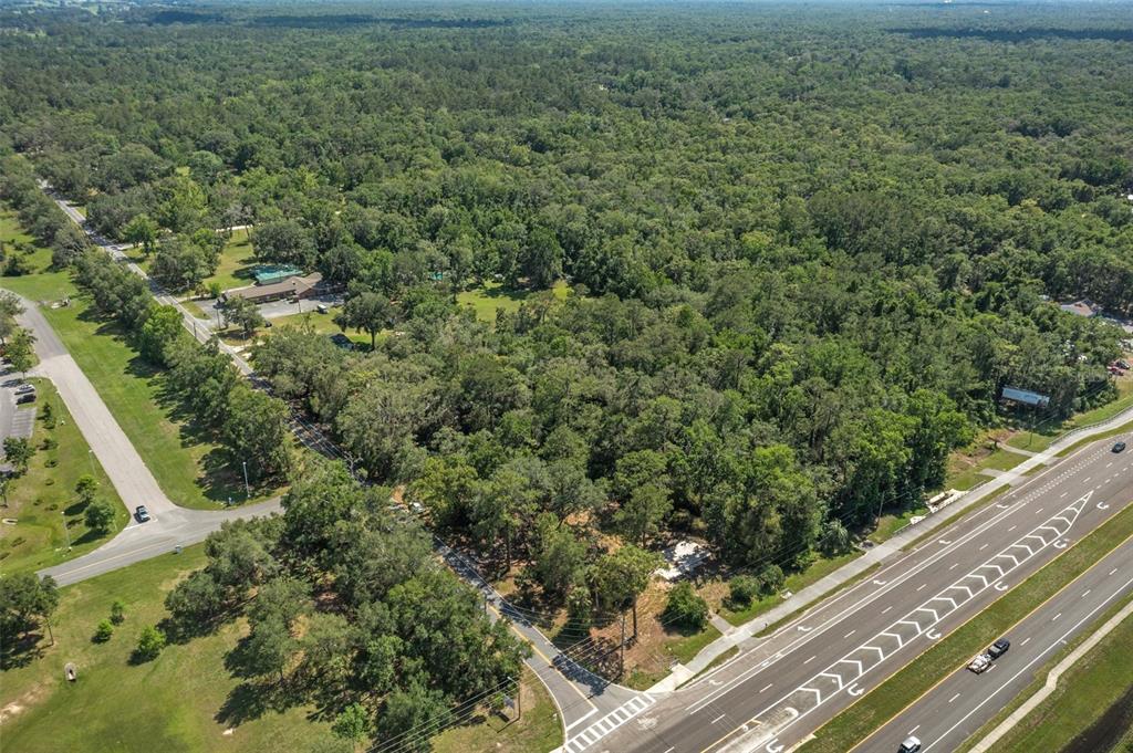 An aerial view shows a wooded lot situated between a multi-lane highway and a road — 17166 CORTEZ BOULEVARD, BROOKSVILLE, FL