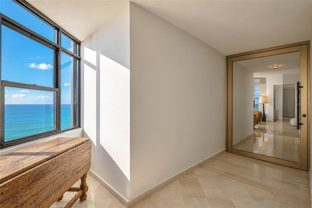 A bright entryway with marble floors, a wooden console table, and a glass-paneled door — 1 C. MANUEL RODRIGUEZ SERRA UNIT 601-A, SAN JUAN, PR