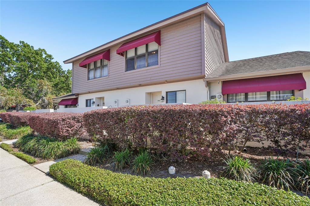 A two-story building with tan siding, red awnings, and a manicured hedge in front — 745 OAK PARK PLACE, BRANDON, FL