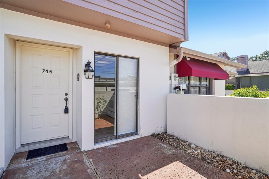The exterior of a home features a white door, sliding glass door, and red awning — 745 OAK PARK PLACE, BRANDON, FL