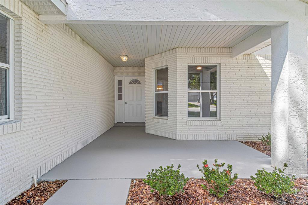 A covered porch with white brick walls leads to a white front door and windows — 9270 SW 92ND PLACE ROAD, OCALA, FL