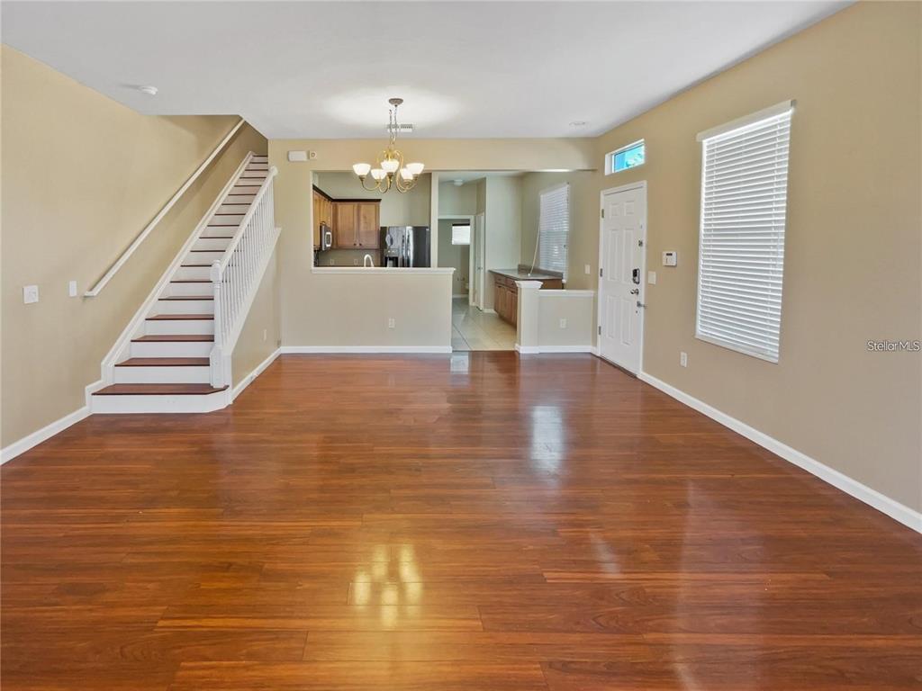 An open living area features hardwood floors, a staircase, and a view into the kitchen — 4970 SW 45TH STREET, OCALA, FL