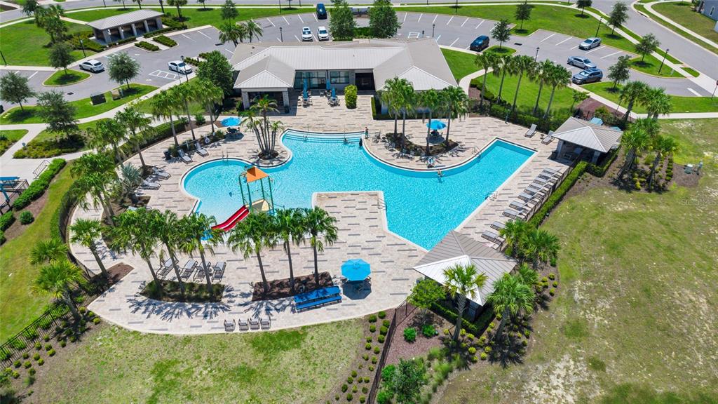 An aerial view shows a community swimming pool with a slide and surrounding patio area — 6939 WILSON PASTURE AVENUE, GROVELAND, FL