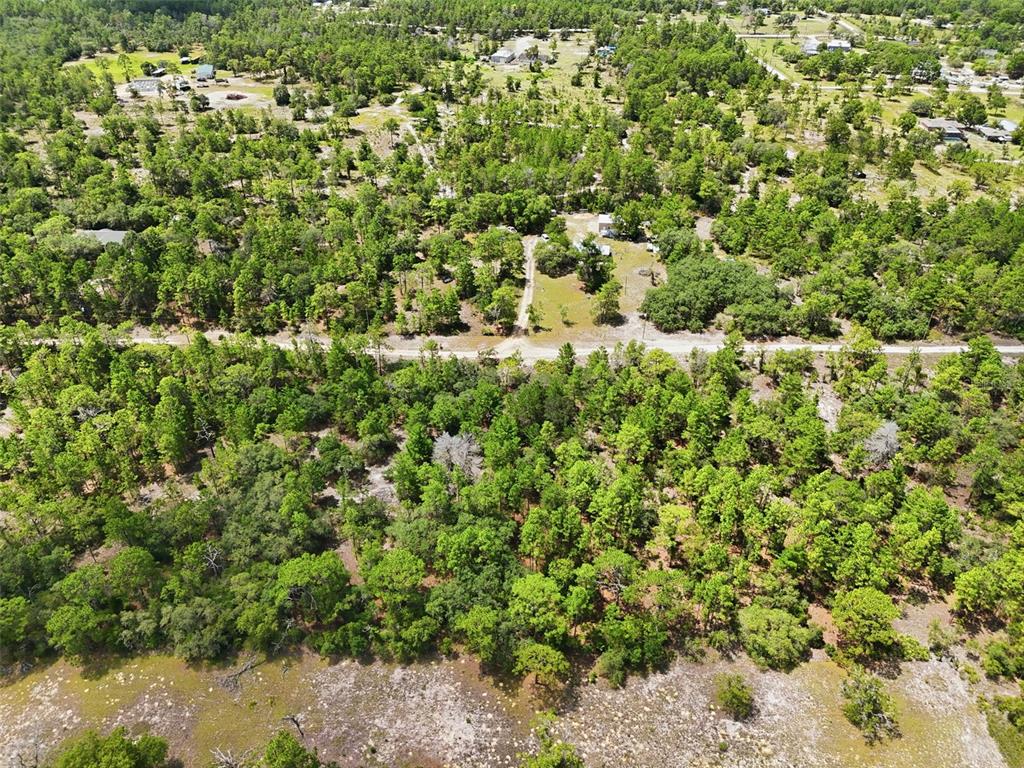 An aerial view shows a wooded lot with a dirt road and scattered residential homes — 0 N MATSONFORD AVENUE, DUNNELLON, FL