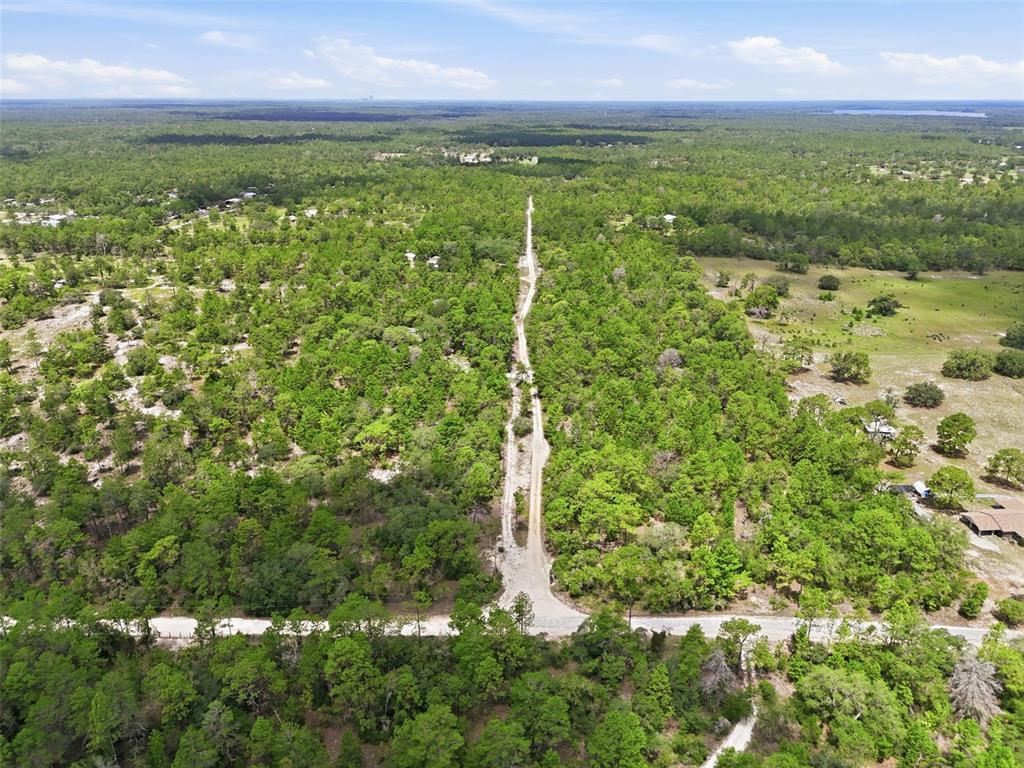 An aerial view shows a dirt road extending through a wooded area toward the horizon — 0 N MATSONFORD AVENUE, DUNNELLON, FL