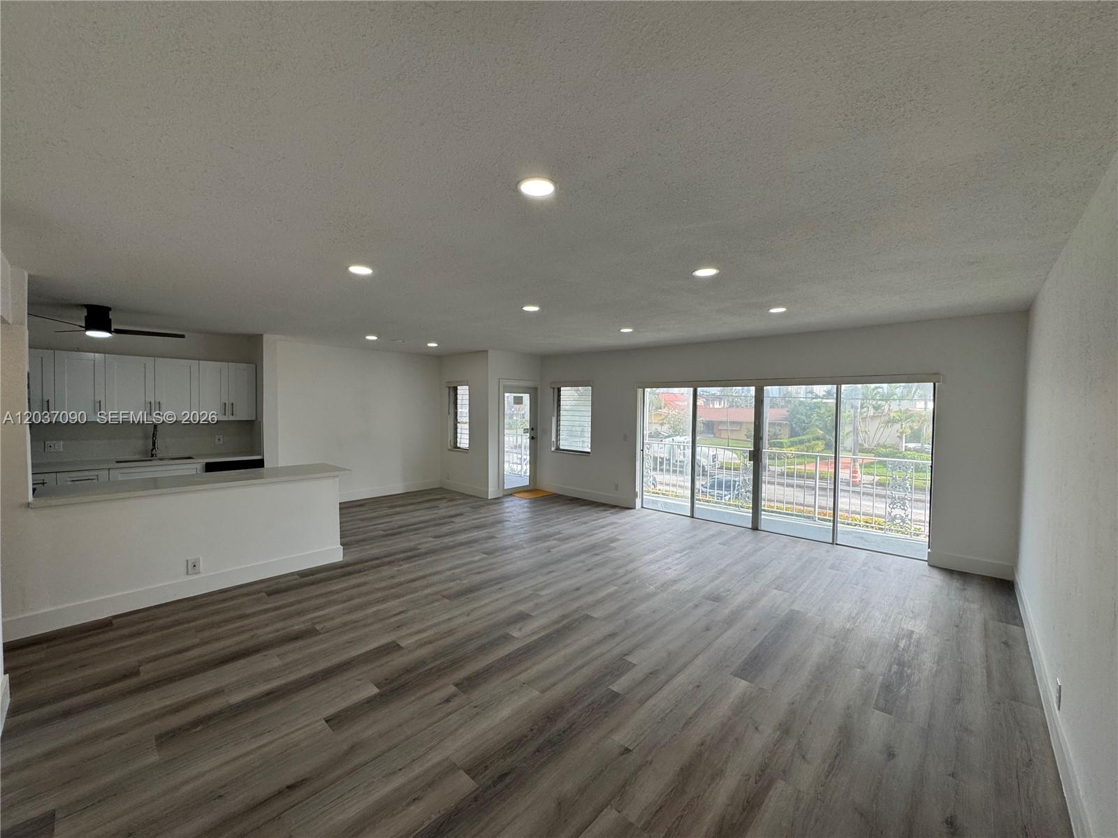 An open-concept living area features light gray wood-look flooring, recessed lighting, and a kitchen peninsula — 630 Layne Blvd # 211, Hallandale Beach FL 33009, HALLANDALE BEACH, FL