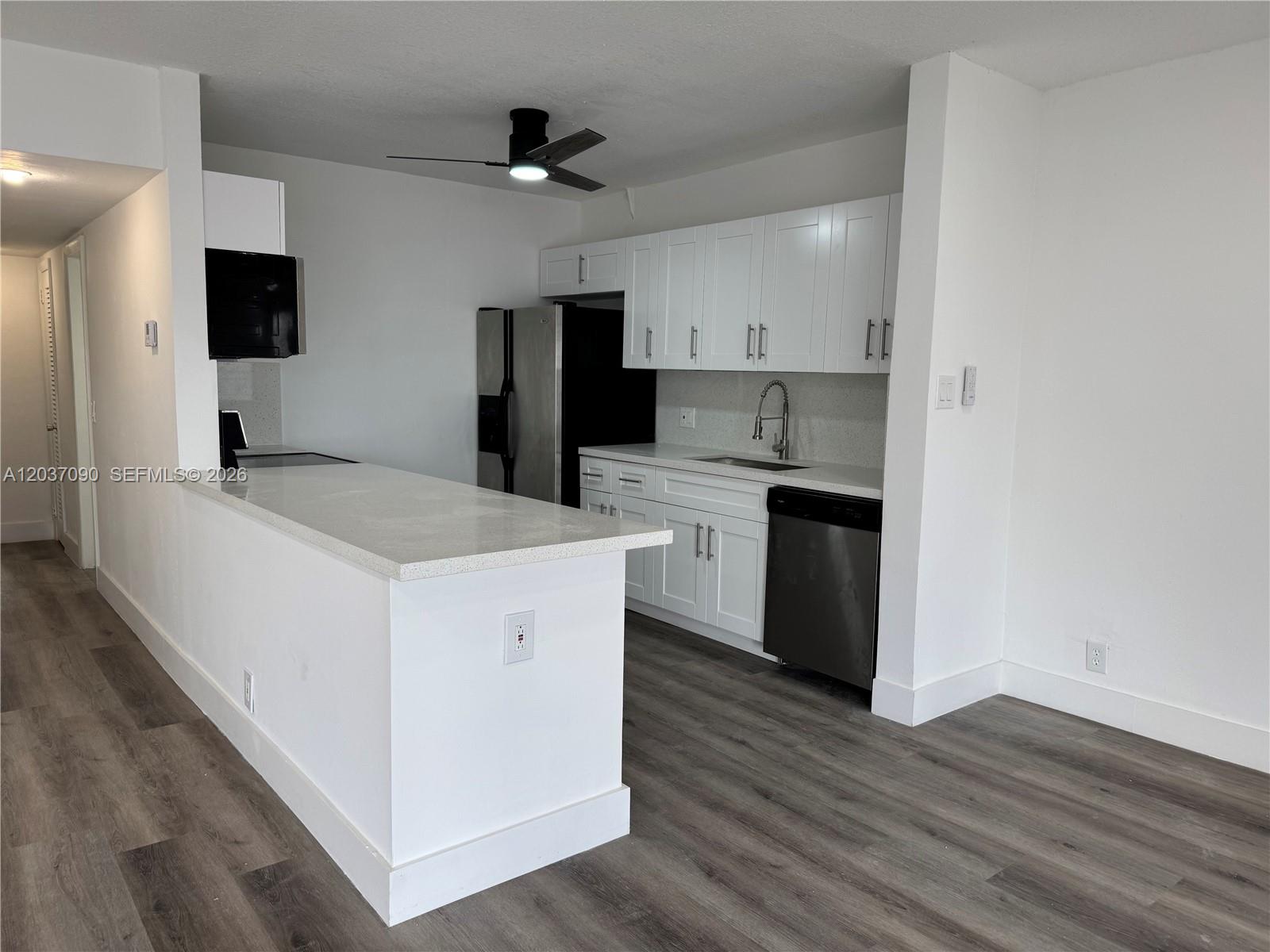 A kitchen features white cabinets, stainless steel appliances, and a peninsula with a countertop — 630 Layne Blvd # 211, Hallandale Beach FL 33009, HALLANDALE BEACH, FL