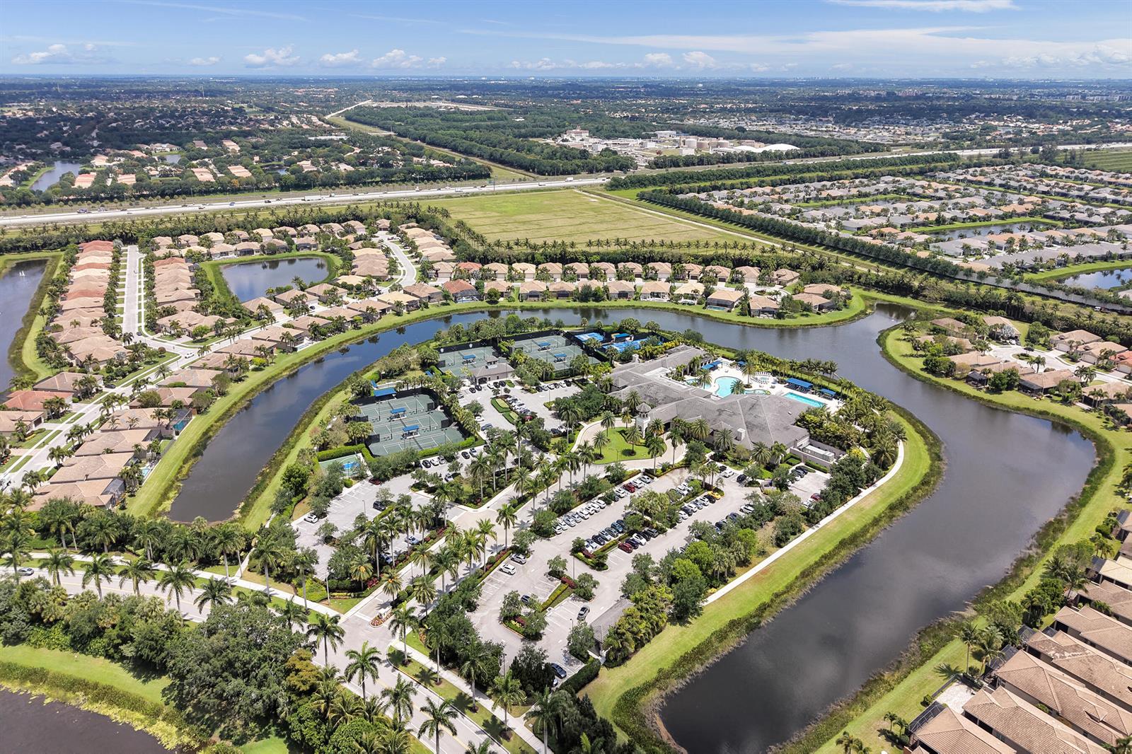 Aerial view of a residential community featuring a clubhouse, tennis courts, and surrounding lakes — 8703 Carmel Mountain Way, Boynton Beach FL 33473, BOYNTON BEACH, FL