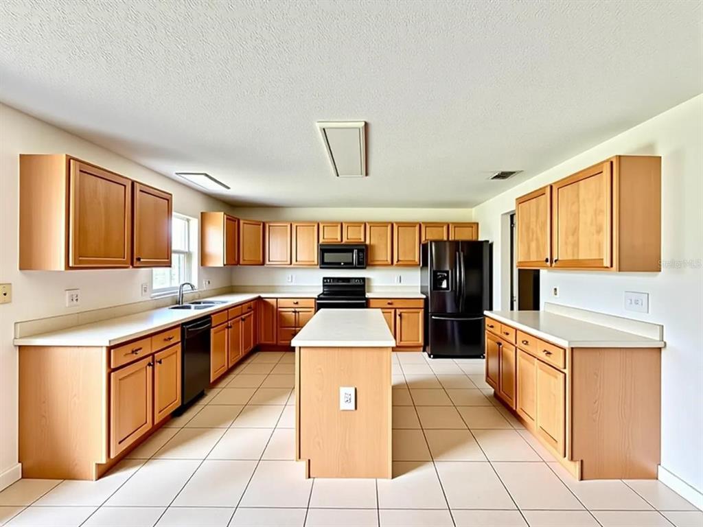 An empty living room features light wood-look flooring, two arched windows, and a staircase — 24301 SW 6TH PLACE, NEWBERRY, FL