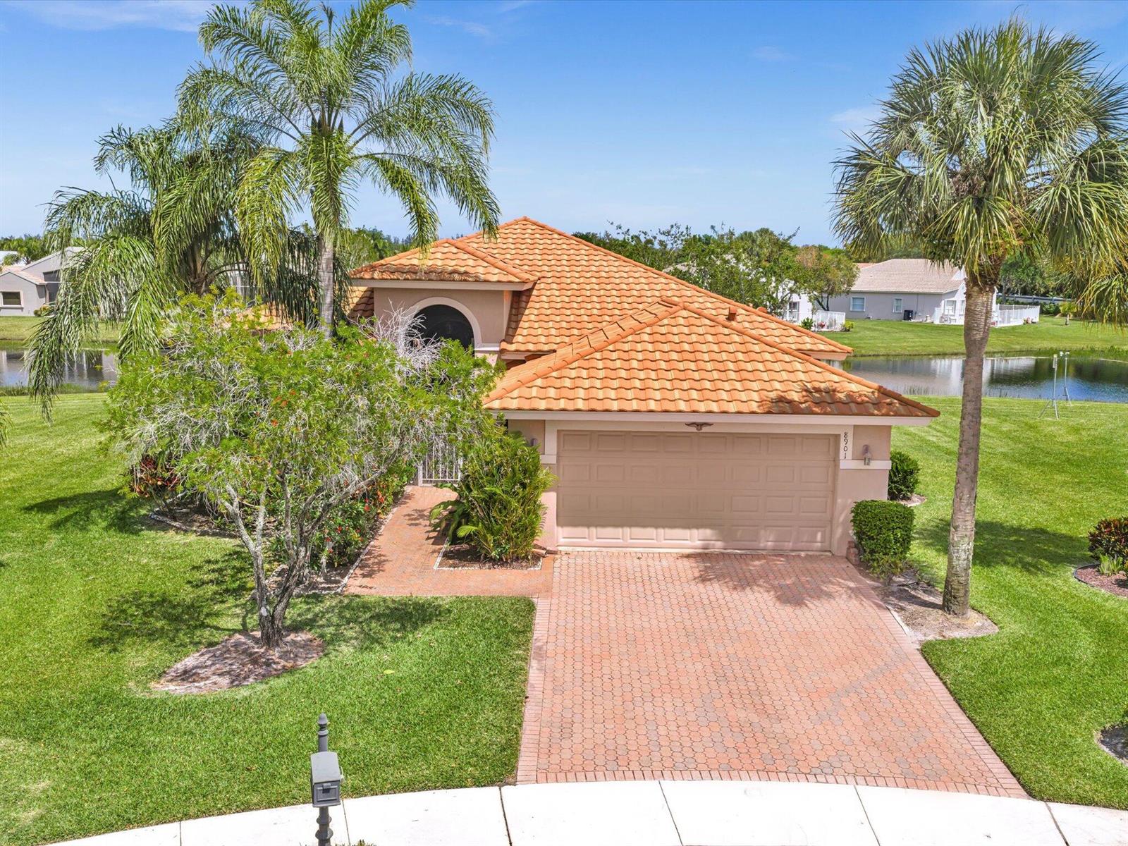 A single-story house with a terracotta tile roof, a brick driveway, and palm trees — 8901 Agliana Circle, Boynton Beach FL 33472, BOYNTON BEACH, FL