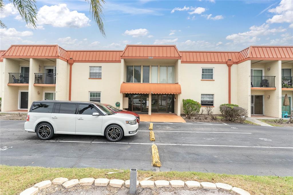 A two-story apartment building with a white brick exterior and a red metal roof — 10365 PARADISE BOULEVARD UNIT 4, TREASURE ISLAND, FL