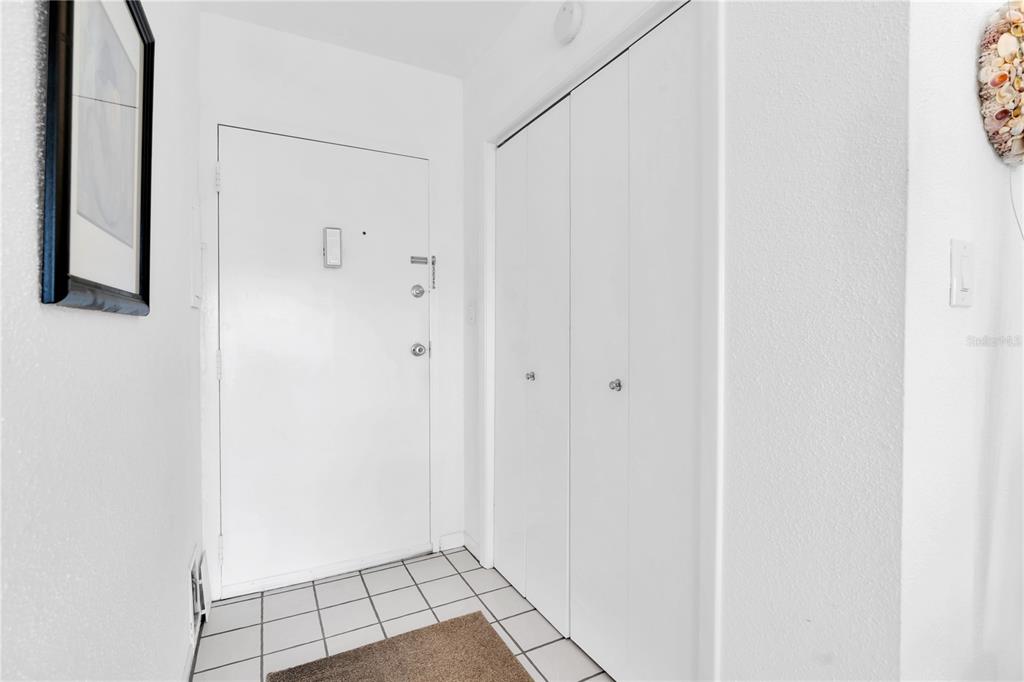 An entryway features a white front door, a white bi-fold closet, and white tiled flooring — 10365 PARADISE BOULEVARD UNIT 4, TREASURE ISLAND, FL