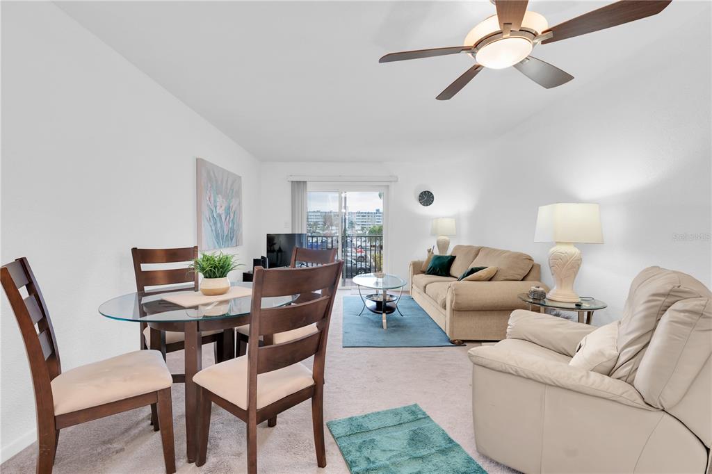 A living and dining room area features a glass table, beige sofa, and ceiling fan — 10365 PARADISE BOULEVARD UNIT 4, TREASURE ISLAND, FL