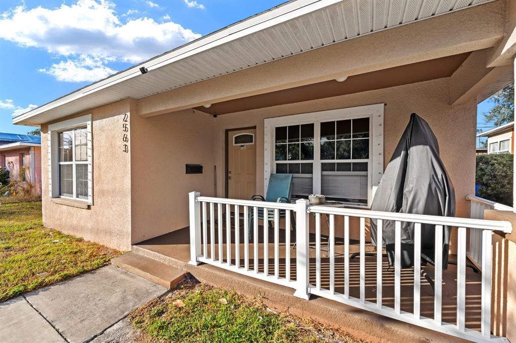 A tan house exterior features a covered front porch with white railings and a door — 2563 13TH AVENUE S, ST PETERSBURG, FL