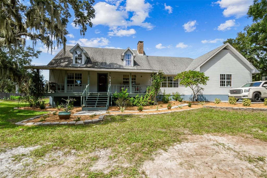 A two-story house with a front porch, dormer windows, and a white truck parked nearby — 15019 CARLTON LAKE ROAD, WIMAUMA, FL