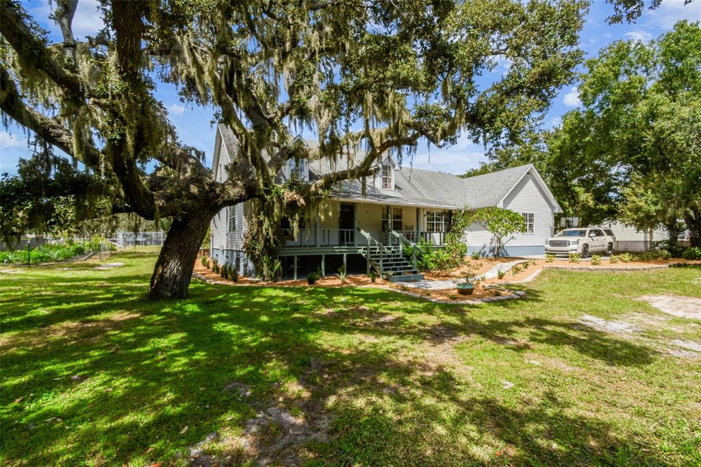A two-story house with a front porch and large oak tree in the front yard — 15019 CARLTON LAKE ROAD, WIMAUMA, FL