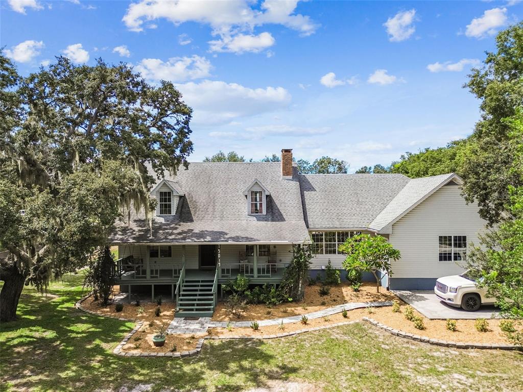 A two-story house with a front porch, dormer windows, and a white vehicle parked nearby — 15019 CARLTON LAKE ROAD, WIMAUMA, FL