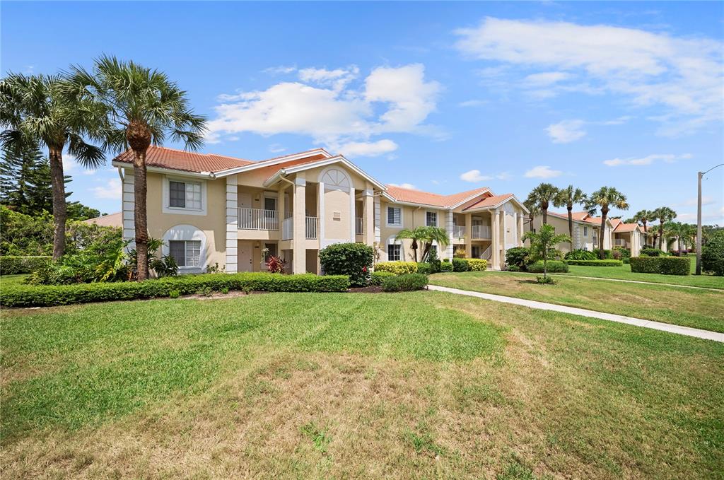 A two-story apartment building with a tan stucco exterior and a red tile roof — 7761 JEWEL LANE UNIT 102, NAPLES, FL