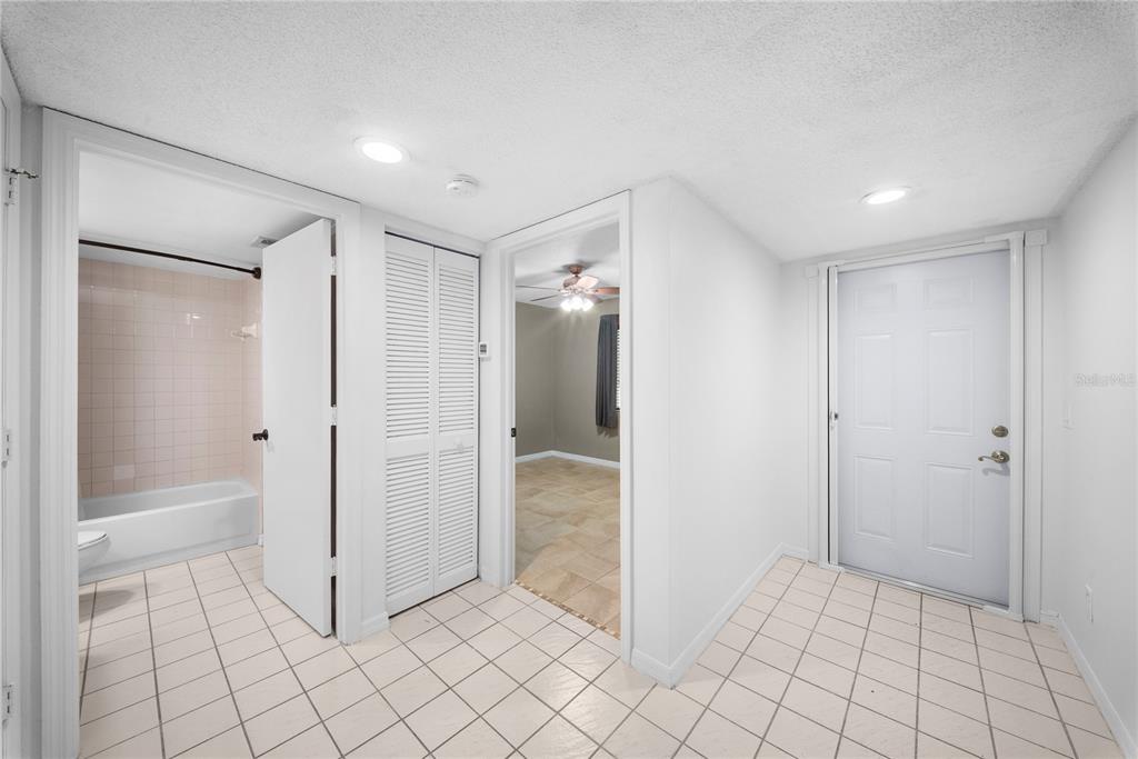 A tiled entryway leads to a bathroom, a closet, and a bedroom with a ceiling fan — 7761 JEWEL LANE UNIT 102, NAPLES, FL