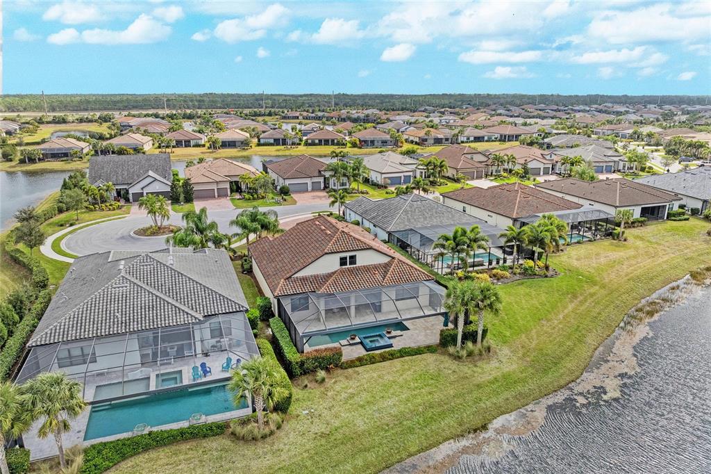 An aerial view of suburban houses with screened-in pools overlooking a lake — 7110 GRADFORD COURT, LAKEWOOD RANCH, FL