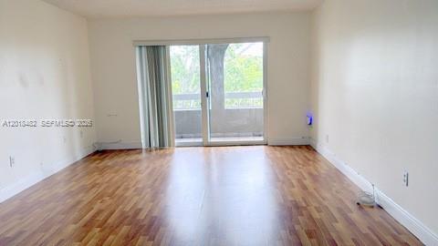 An empty room with wood-look flooring and a sliding glass door leading to a balcony — 7815 Camino Real # i417, Miami FL 33143, MIAMI, FL