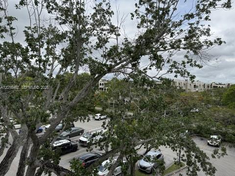 An elevated view shows a parking lot surrounded by trees and residential buildings under a cloudy sky — 7815 Camino Real # i417, Miami FL 33143, MIAMI, FL