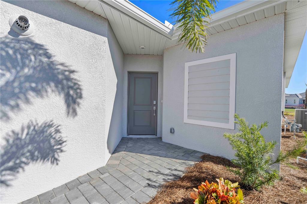 A paved walkway leads to the gray front door of a house with stucco walls — 14916 ANCHORAGE ROAD, PUNTA GORDA, FL
