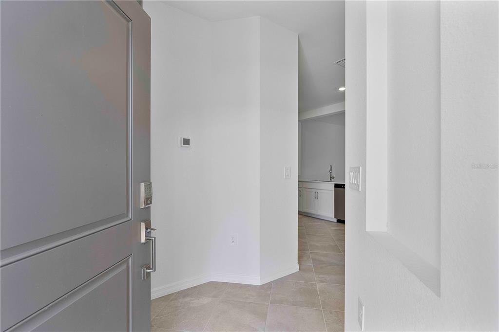 A view from an open front door into a tiled entryway leading toward a kitchen — 14916 ANCHORAGE ROAD, PUNTA GORDA, FL