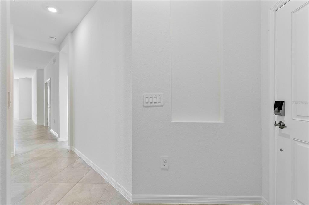 A bright hallway with light-colored tile flooring, white walls, and a recessed wall panel — 14916 ANCHORAGE ROAD, PUNTA GORDA, FL