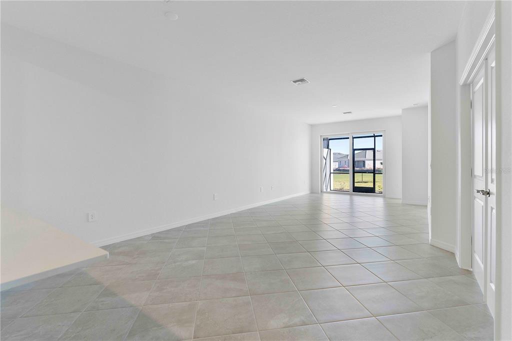 A spacious, empty room features white walls, light-colored tile flooring, and a sliding glass door — 14916 ANCHORAGE ROAD, PUNTA GORDA, FL