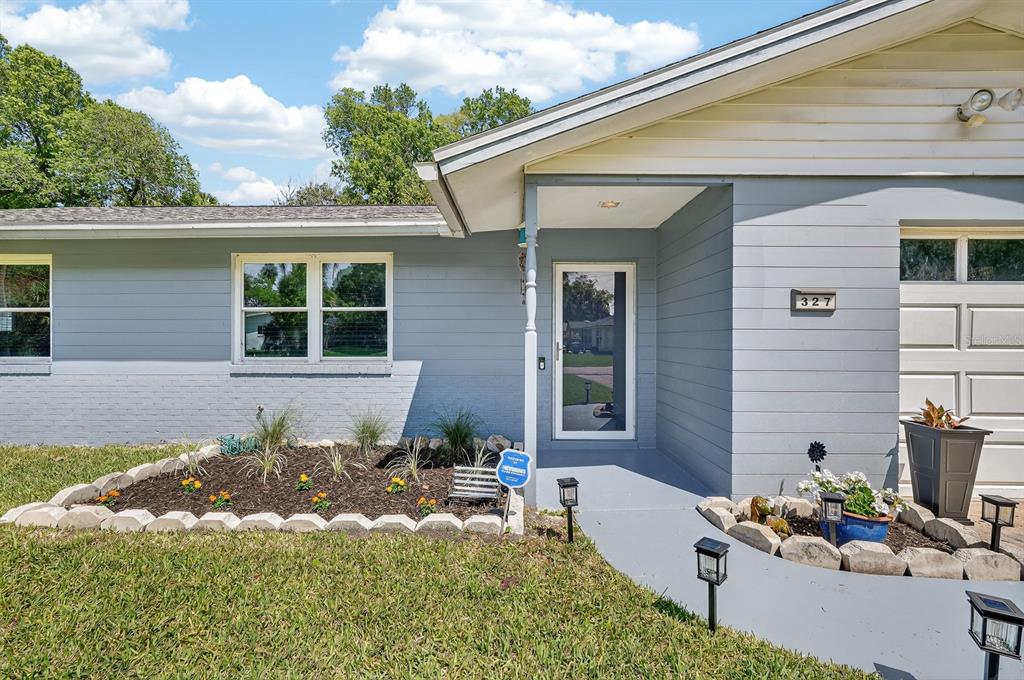 The exterior of a light gray house features a front entrance, landscaping, and a driveway — 327 LONDON ROAD, DAYTONA BEACH, FL