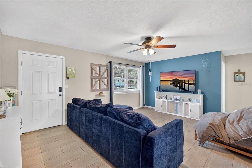 A living room features a blue accent wall, a dark blue sofa, and tile flooring — 327 LONDON ROAD, DAYTONA BEACH, FL