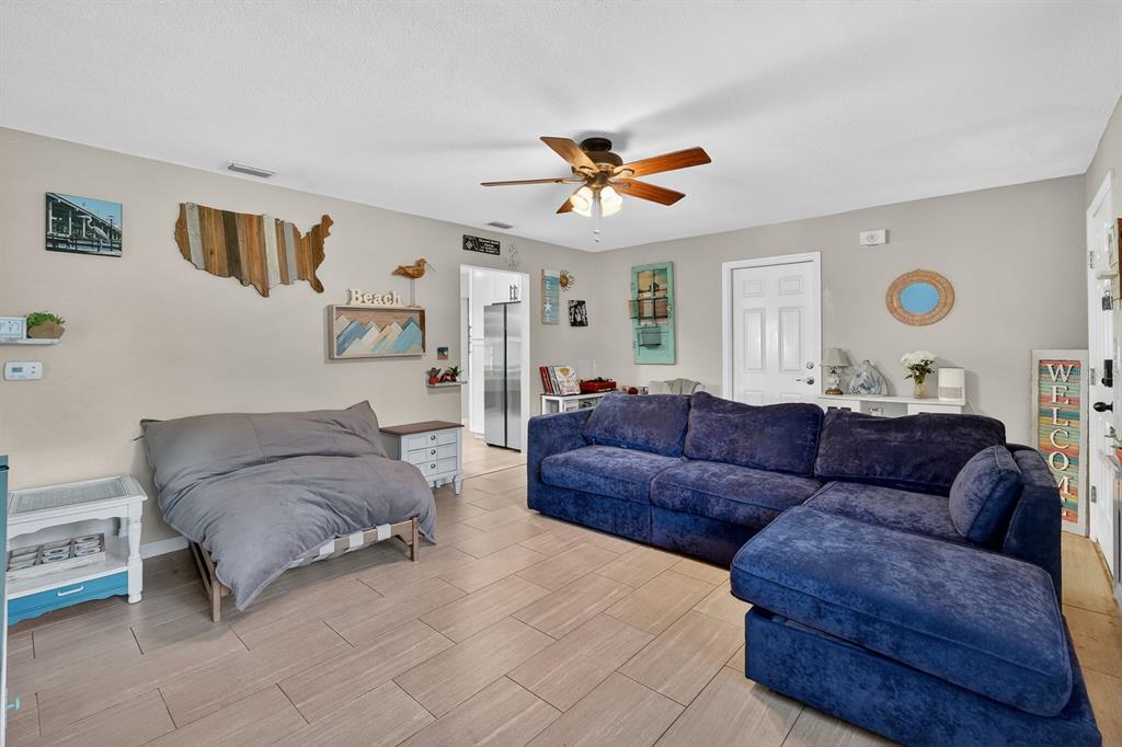 A living room features a blue sectional sofa, a gray futon, and tile flooring — 327 LONDON ROAD, DAYTONA BEACH, FL