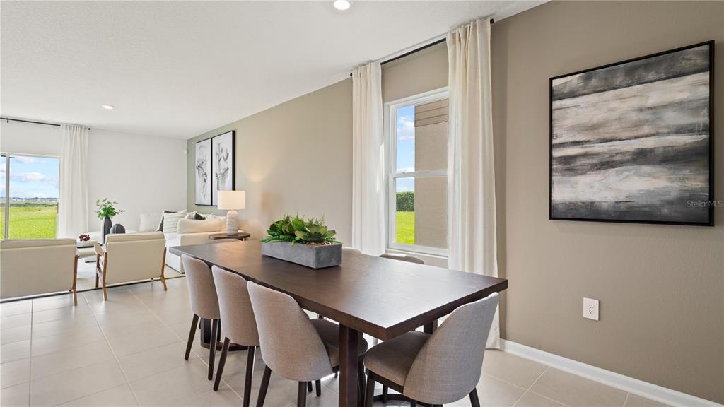 A dining area with a dark wood table and chairs sits adjacent to a living room — 6225 BOTTICELLA BOULEVARD, WINTER HAVEN, FL
