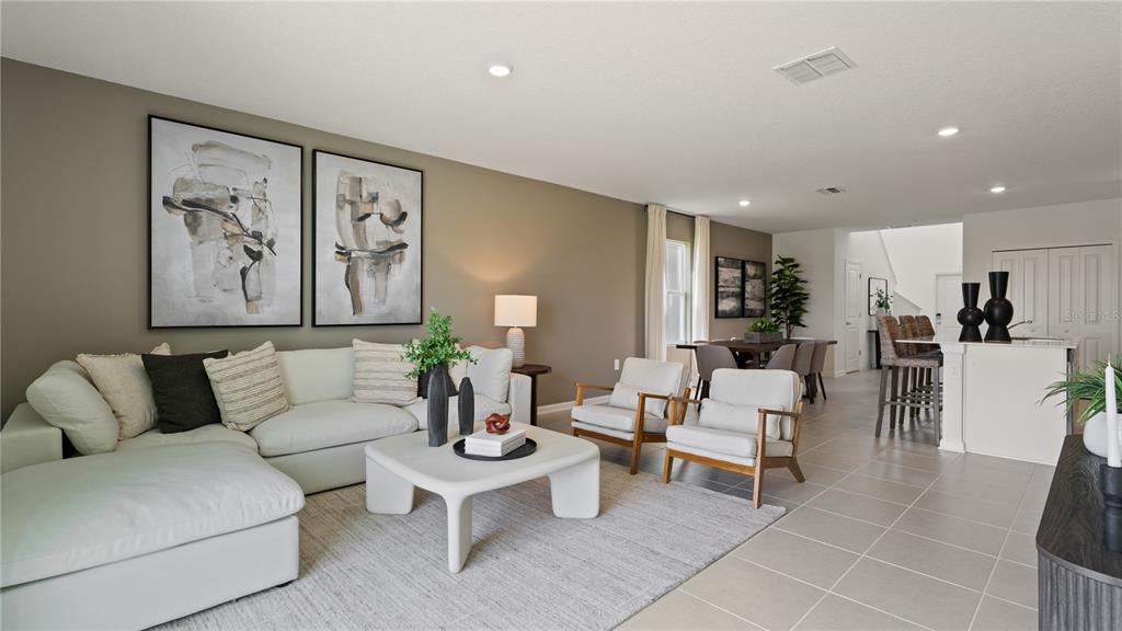A bright, open-concept living room features a white sectional sofa, two armchairs, and dining area — 6225 BOTTICELLA BOULEVARD, WINTER HAVEN, FL
