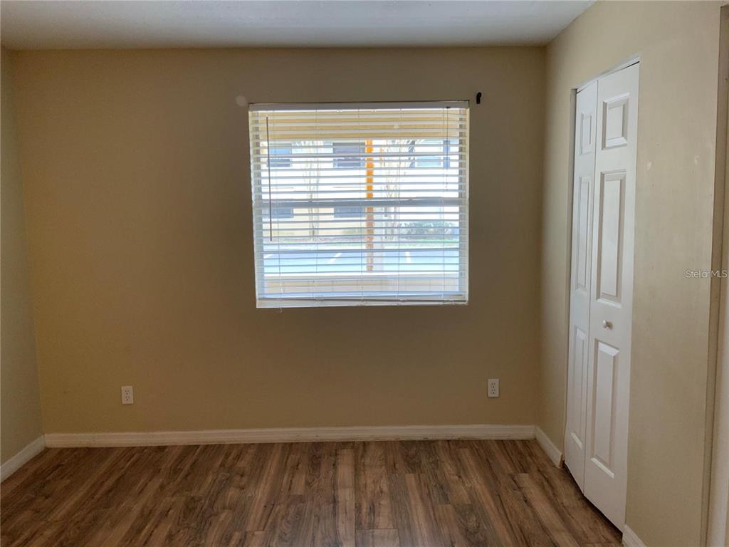 A bedroom with light-colored walls, wood-look flooring, a window with blinds, and a closet — 233 RED MAPLE PLACE UNIT 233, BRANDON, FL