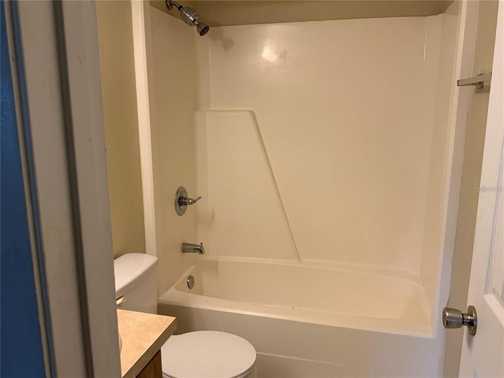 A bathroom features a white bathtub and shower surround with a chrome faucet and handle — 233 RED MAPLE PLACE UNIT 233, BRANDON, FL