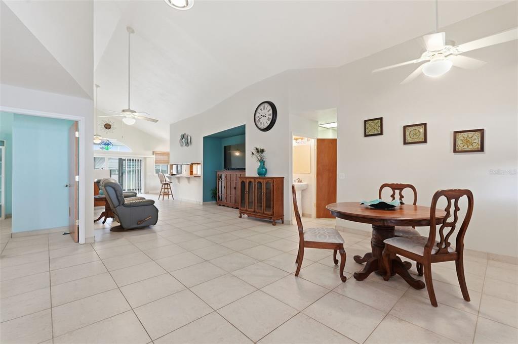 A dining area and living room with vaulted ceilings, tile floors, and a ceiling fan — 585 SELLARS DRIVE, LAKE ALFRED, FL