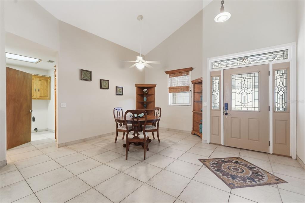 A dining area with tile floors, a vaulted ceiling, and a front door with sidelights — 585 SELLARS DRIVE, LAKE ALFRED, FL