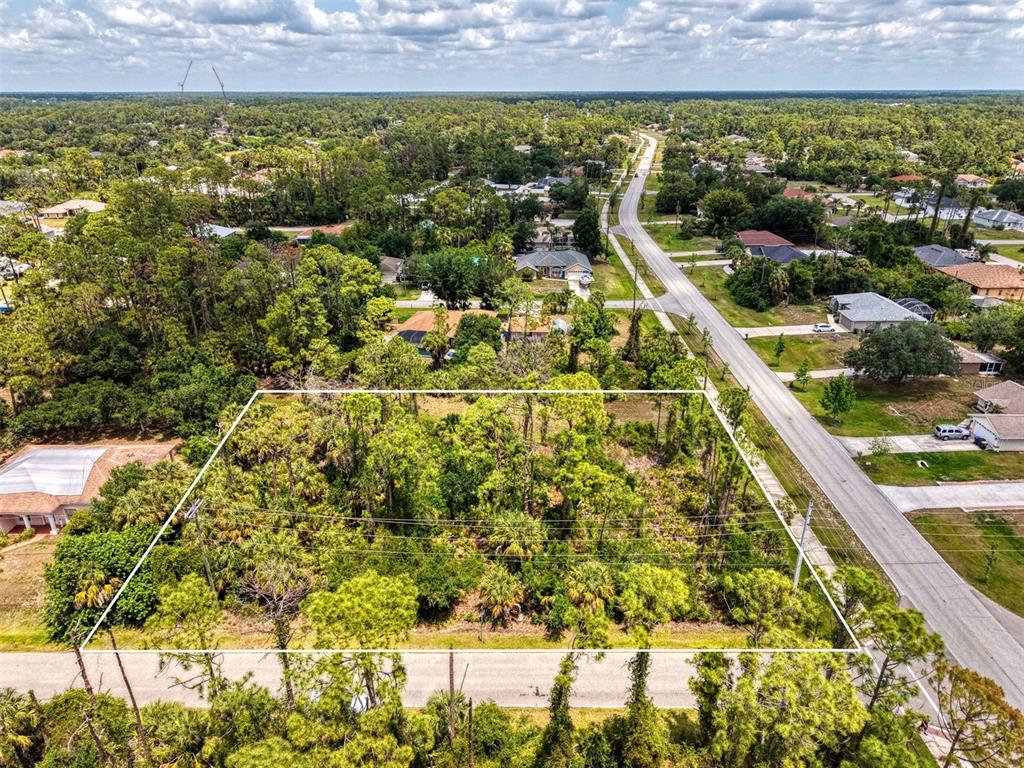 An aerial view shows a rectangular, wooded vacant lot bordered by residential streets and houses — FONSICA AVENUE, NORTH PORT, FL