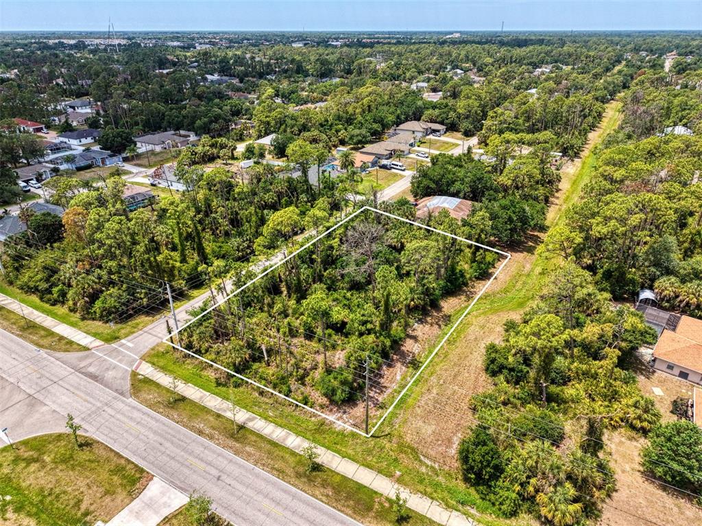 An aerial view shows a vacant, wooded rectangular lot outlined in white near a road — FONSICA AVENUE, NORTH PORT, FL