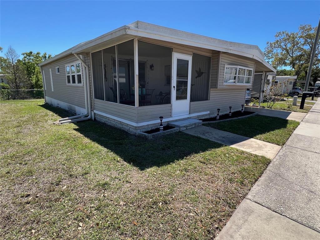 A single-story mobile home with tan siding and a screened-in front porch — 29250 US HIGHWAY 19 N UNIT 294, CLEARWATER, FL