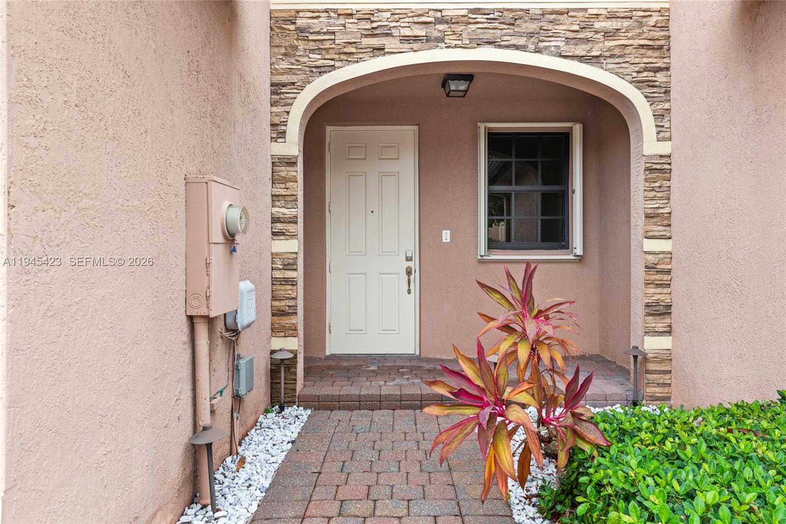 A paved walkway leads to a front door under an arched stone-accented entryway — 3777 SE 3rd St, Homestead FL 33033, HOMESTEAD, FL