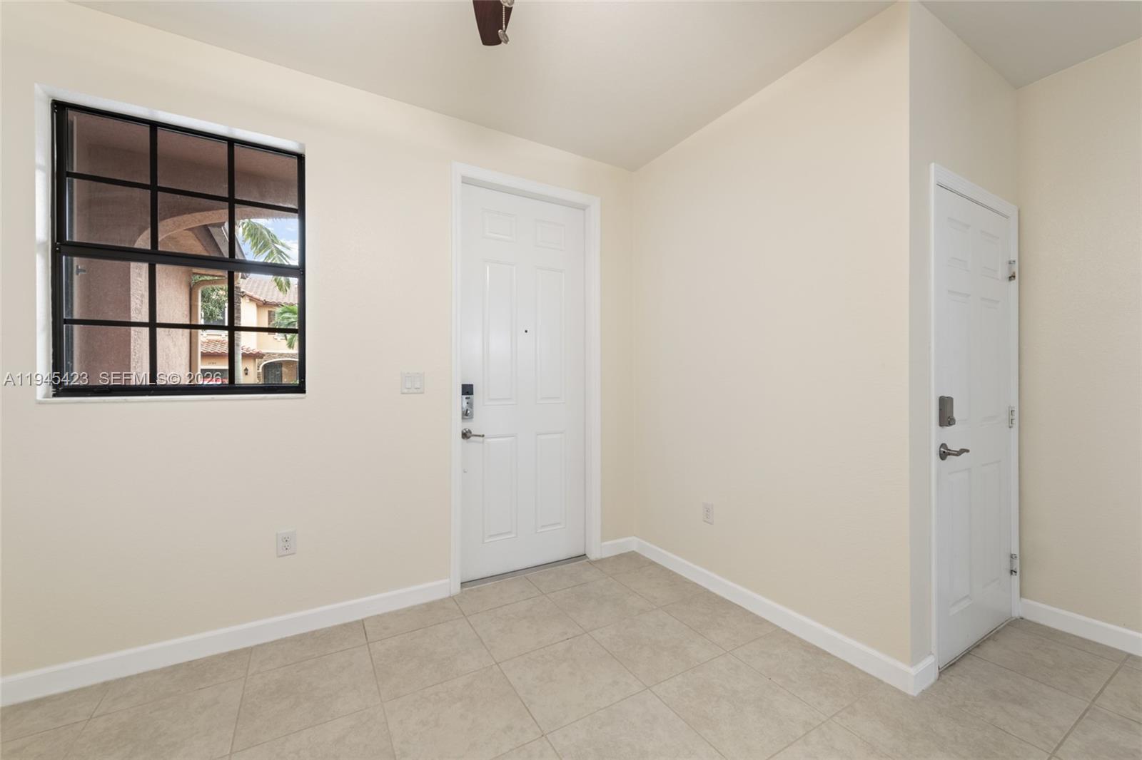An entryway features beige tile flooring, two white doors, and a window with black grids — 3777 SE 3rd St, Homestead FL 33033, HOMESTEAD, FL